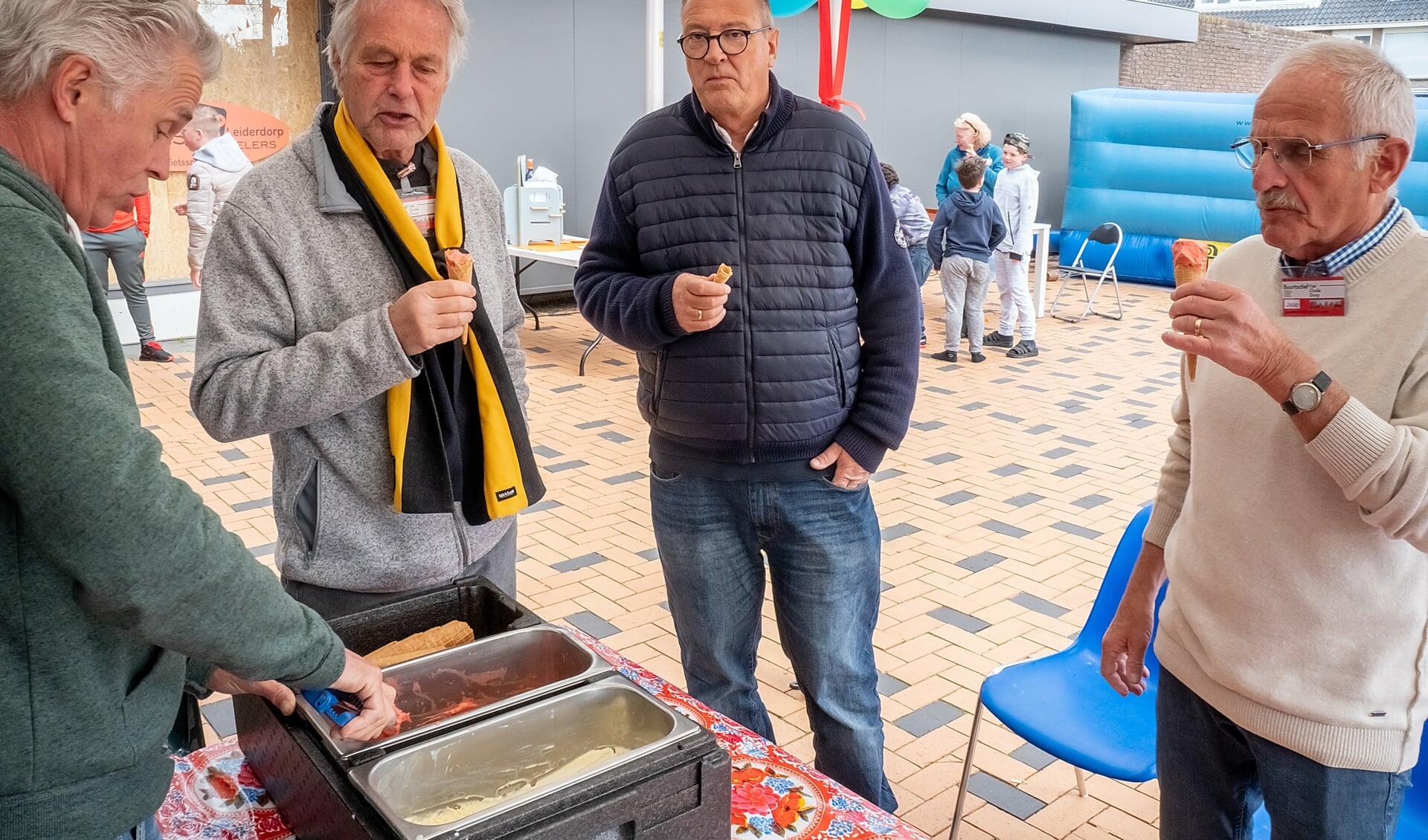 Bestuursleden Robert Laan (tweede van links) en Jaap Timmermans (geheel rechts) genieten van een ijsje op het verjaarsfeest van \t Buurthuis. | Foto: J.P. Kranenburg