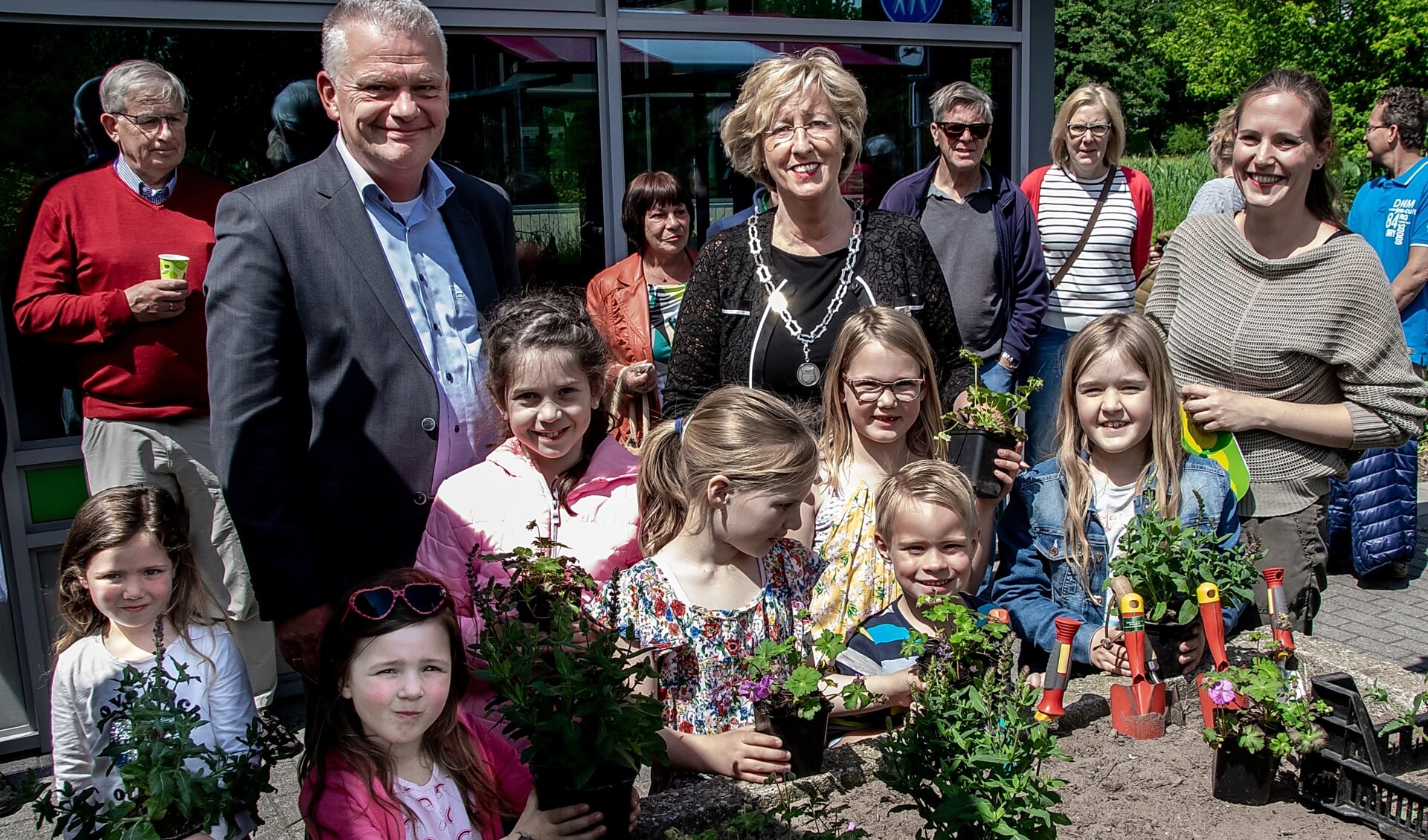 Wethouder Daan Binnendijk, burgemeester Laila Driessen en MEC medewerkster Marieke Weishaupt met een aantal jonge natuurliefhebbers bij de  plantenbak, waarin vlak voor de opening de laatste plantjes gezet werden. 