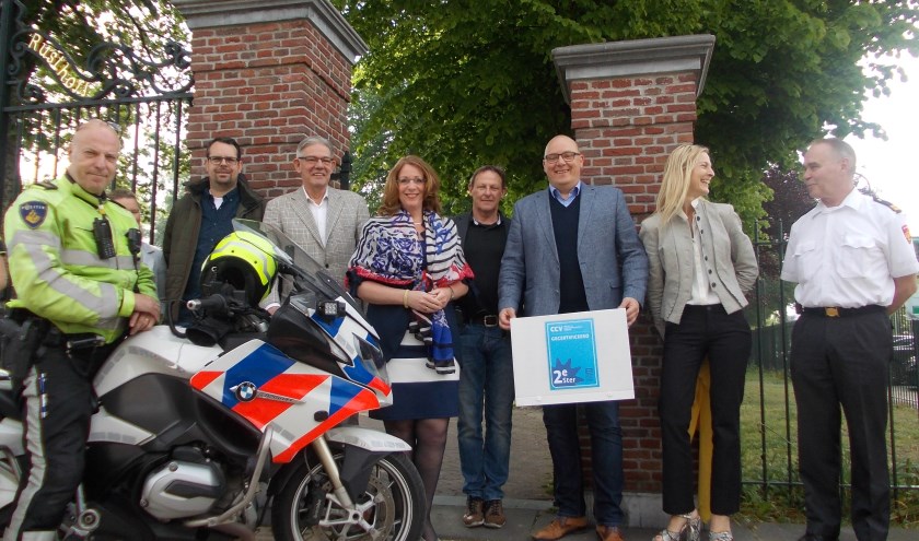 De tweede tegel van het Keurmerk Veilig Ondernemen in Sassenheim. Carla Breuer, John van der Tol, politie, brandweer, ondernemers en ambtenaren kijken toe. | Tekst en foto: Piet de Boer