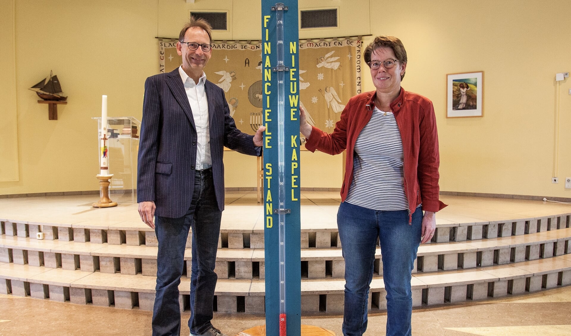 Gert Binnendijk en Astrid Buskermolen bij de thermometer, waarop de stand wordt bijgehouden. | Foto: Adrie van Duijvenvoorde 
