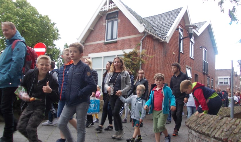 De deelnemers met hun begeleiders wurmen zich door het Schoollaantje. | Foto: Piet de Boer.