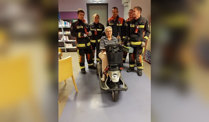 Egberdien Keesenberg met de brandweerploeg die haar scootmobiel uit de lift wist te krijgen. "Ongelooflijk hoe ze dat voor elkaar hebben gekregen, met de zware accu's is het een heel gewicht." | Foto: PR