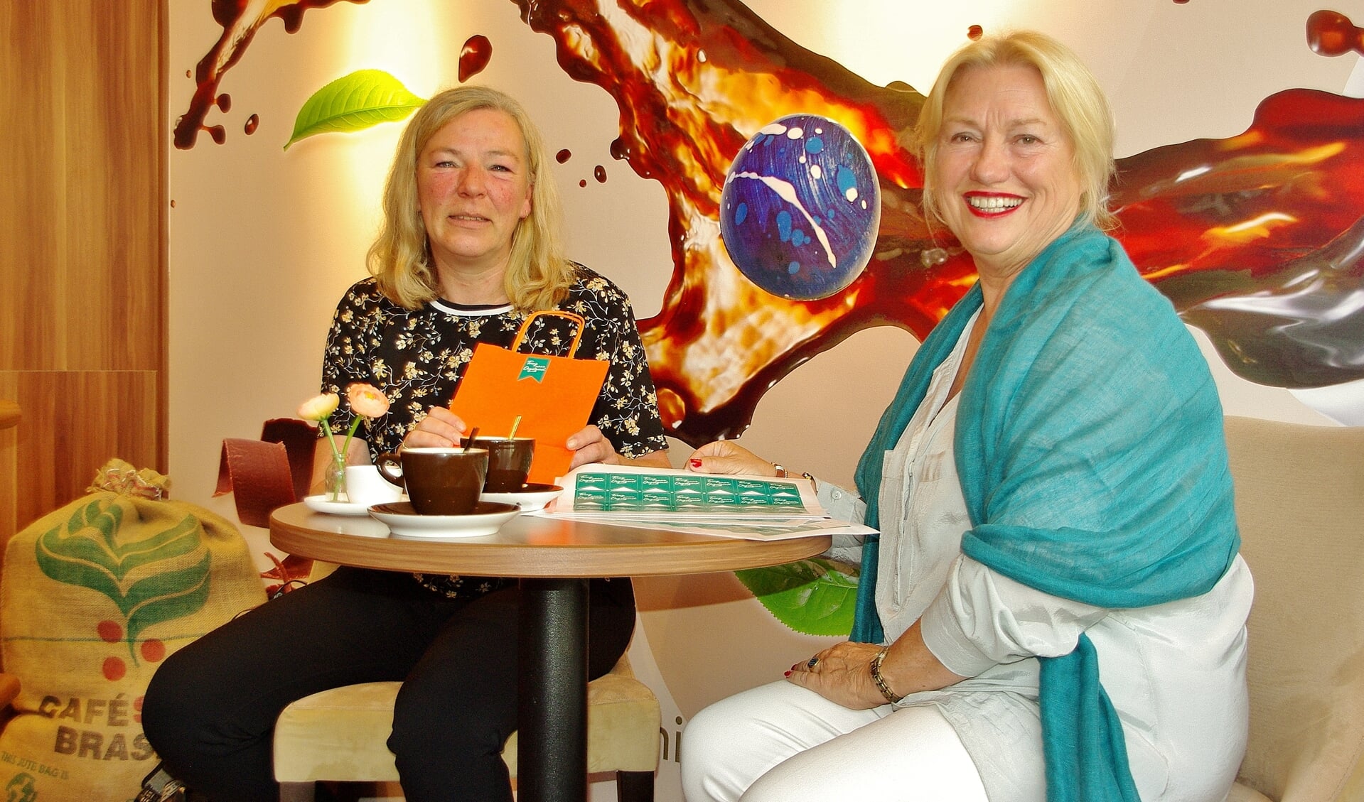 Marjolijn van der Jagt overhandigt de eerste Terug naar Oegstgeest-stickers aan Karen Welter van de Koffiemeulen.