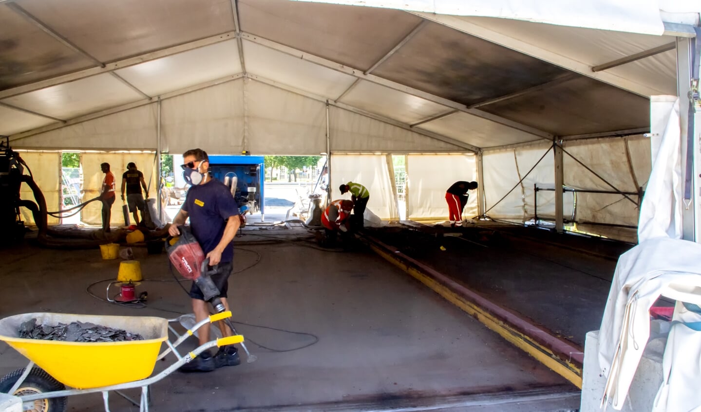 In de tent wordt hard gewerkt aan het verwijderen van de slijtlaag op het asfalt.  