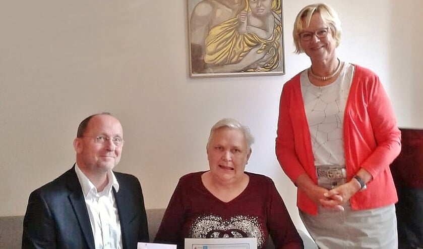 Jolanda Meerman, cliënte bij GGZ Rivierduinen, overhandigt de opbrengst van haar expositie aan het Rode Kruis.