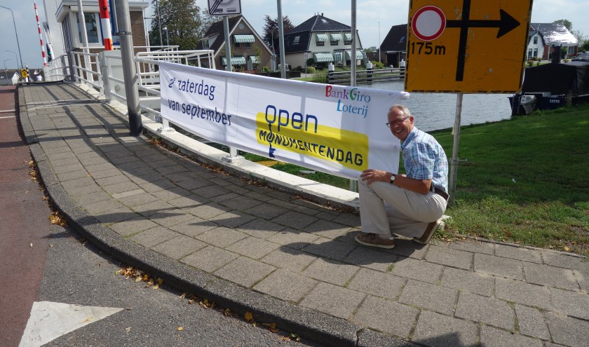 Eric Prince, voorzitter "Oud Lisse" en van het Comité Open Monumentendag Lisse, knoopt eigenhandig het spandoek aan de brug.