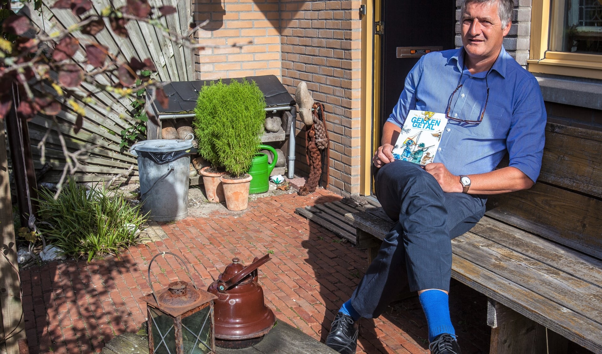 Piet Rovers in zijn Katwijkse voortuin met zijn verhalenbundel ‘Gekkengetal’. | Foto: Adrie van Duijvenvoorde