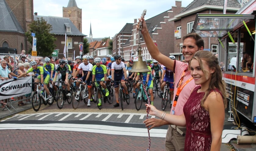 Wethouder ter Hark, bijgestaan door de bloemenkoningin, luidt de startbel voor de traditionele kermiskoers. | Foto: WS