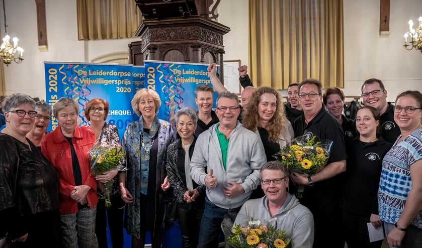 Burgemeester Driessen (vijfde van links) tussen de winnaars van de vrijwilligersprijzen: links en direct rechts van Driesen de dames van het Dagprogramma Senioren, in de grijze vesten bestuursleden van buurtvereniging Op Dreef en rechts de vrijwilligers die het huttenbouwen en Halloween-spookhuis organiseerden. Daarbij ontbreken 'de Plaagmeesters', belangrijke partners bij de organisatie van het Halloween spookhuis.