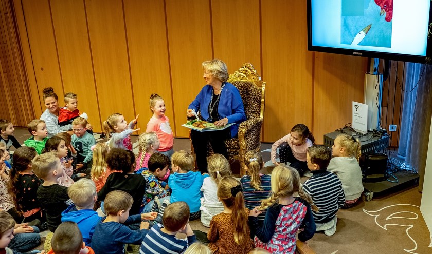 Burgemeester Driessen, gezeten in de voorleesstoel die meegekomen was uit de bibliotheek, vertelt het verhaal van Moppereend aan zestig enthousiaste kleuters.
