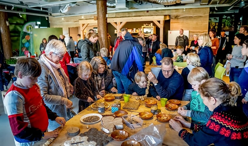 Jong en ouder werken ijverig aan het maken van pindaslingers. | Foto: J.P. Kranenburg