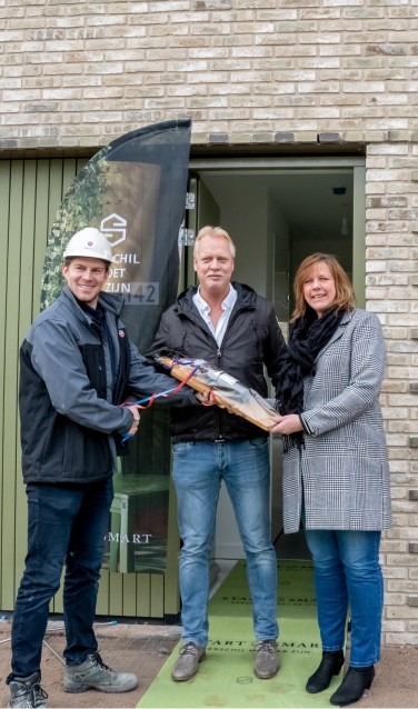Freek Cramer, uitvoerder van Vink Bouw, overhandigt Anja en Jan Hospers de sleutel van hun huis plus een fles wijn.