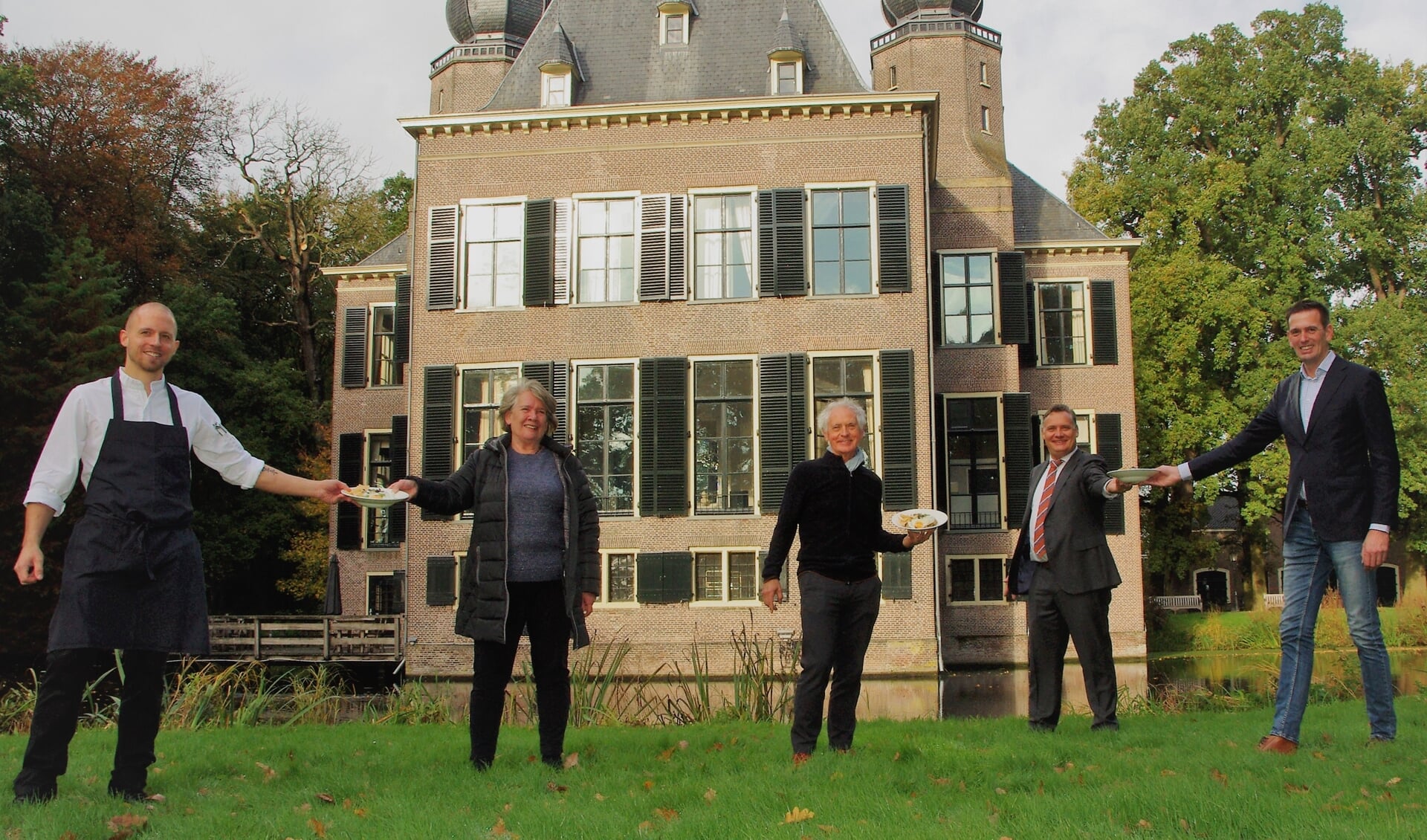Chef-kok Erik van der Hulst (l) en directeur Jan-Willem Besselink (tweede van rechts) van Oud Poelgeest overhandigen de eerste maaltijden aan Eveline Idema en Hugo Brouwer (Voedselbank Leiden), en Arthur van Elzelingen (r) (Voedselbank Teylingen). | 