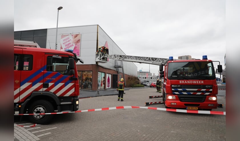 De brandweer probeert het losgewrikte geveldeel weer vast te zetten.
