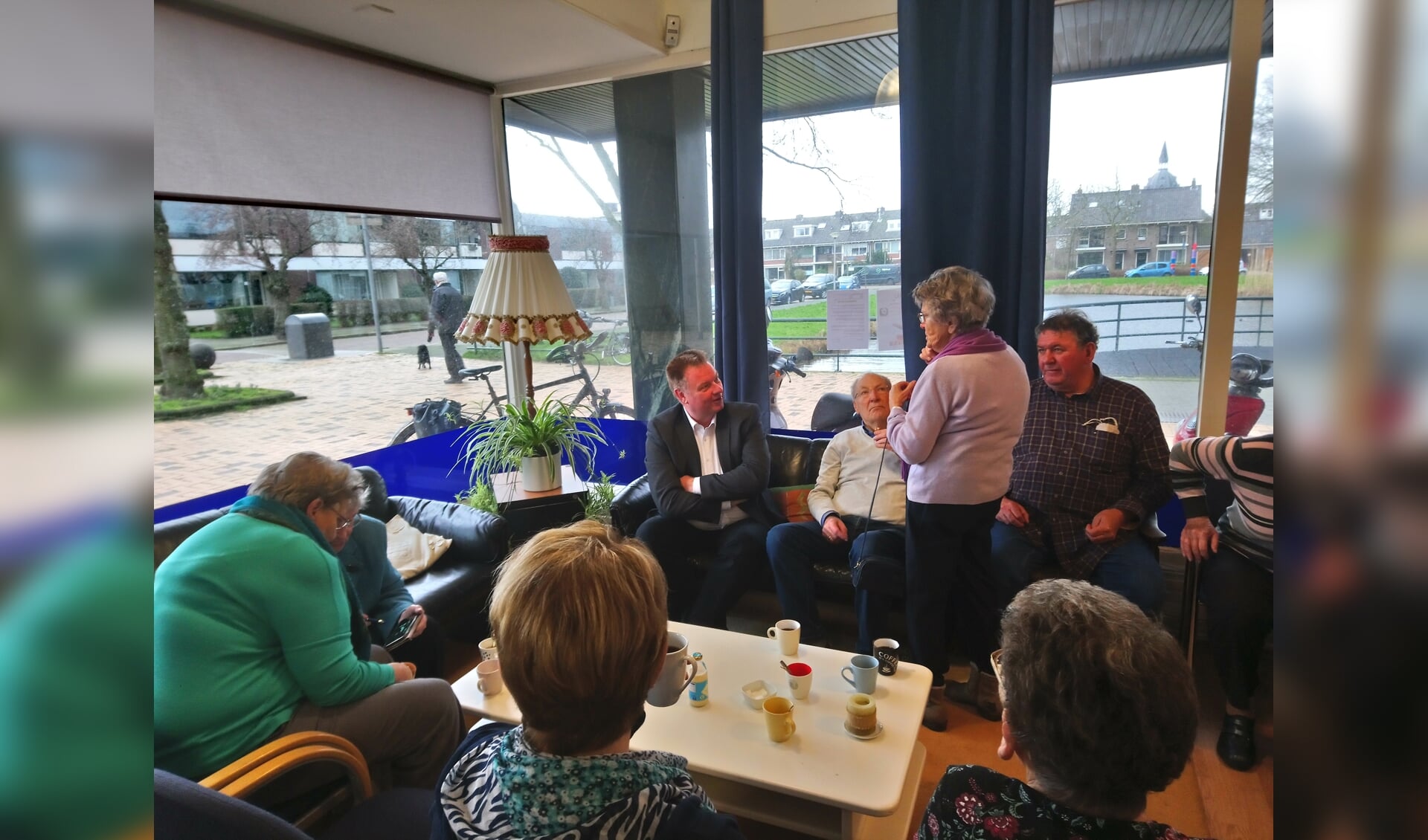 Rik van Woudenberg (geheel links op de bank) in gesprek met de bezoekers van 't Buurthuis.  