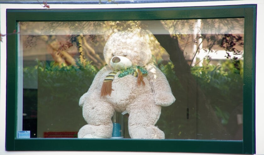 Een knuffelbeer kijkt aan de Oranjelaan nieuwsgierig naar buiten of er al kinderen langs wandelen. |