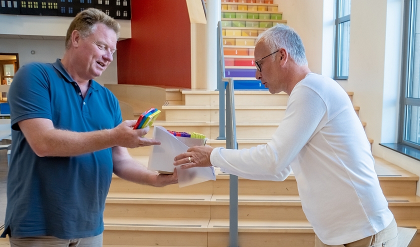 Wethouder Rik van Woudenberg overhandigt chocoladerepen aan directeur René Martens van de Prins Willem-Alexanderschool.
