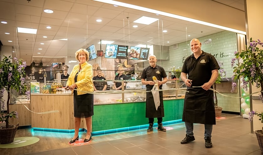 Burgemeester Laila Driessen en Bart Bos knippen het lint door terwijl eigenaar Bertus Bos toekijkt.