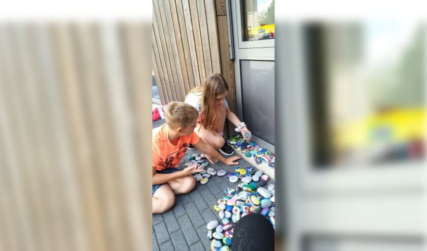 Leerlingen van Daltonschool De Leeuwerik leggen beschilderde keien bij de school.