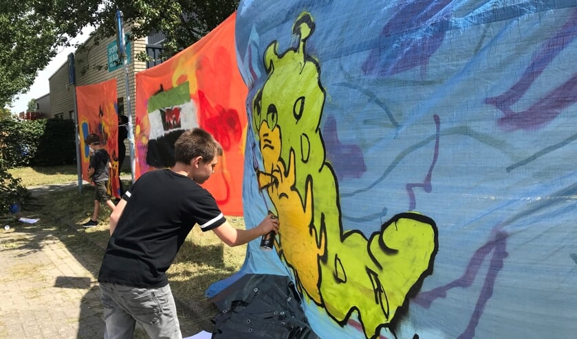 Quinten werkt aan zijn graffiti kunstwerk.