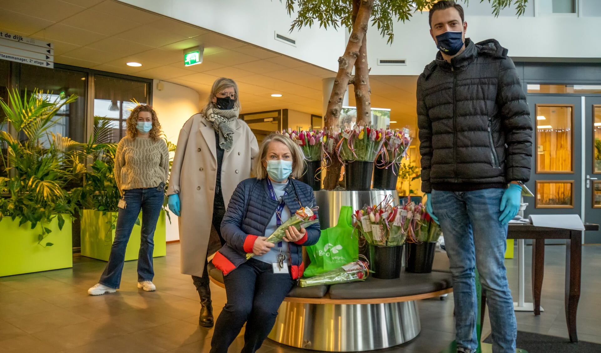 Linda Bezuijen (met beige jas) en Sjoerd Verbree van Vegro overhandigden de tulpen aan medewerkers van De Ommedijk. | Foto: J.P. Kranenburg