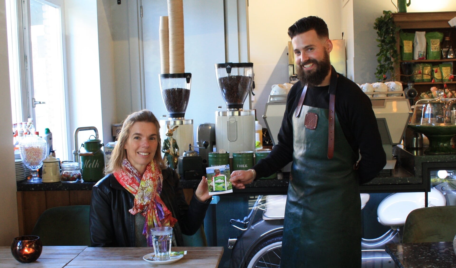 Miriam van der Wee van werkgroep Teylingen Fairtrade overhandigt Tommy van den Berg van Nozemskoffie de eerste kaart met theezakje.