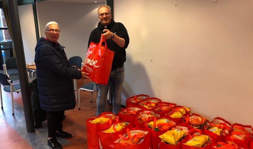 <p>Pastoor Bosma overhandigt de tassen aan de voedselbank. </p>