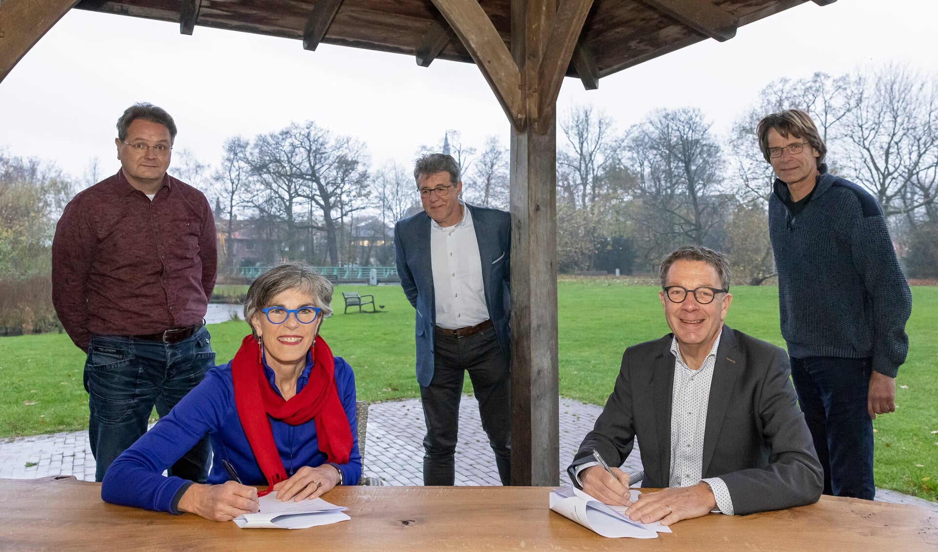 Wethouder Heleen Hooij  en voorzitter Paul ten Velden (r) ondertekenen de overeenkomst, onder toeziend oog van de bestuursleden van de Stichting Beheer Park Rusthoff. 