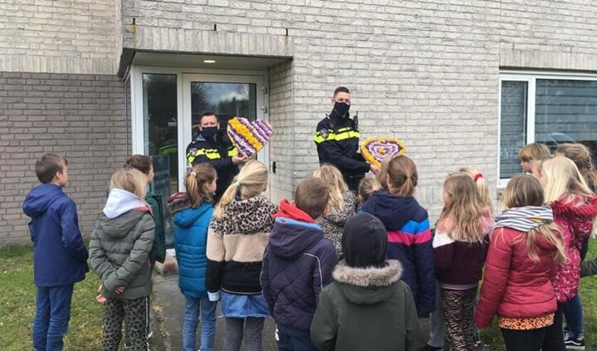 De wijkagenten krijgen een corsohart cadeau van leerlingen van de Overplaats.
