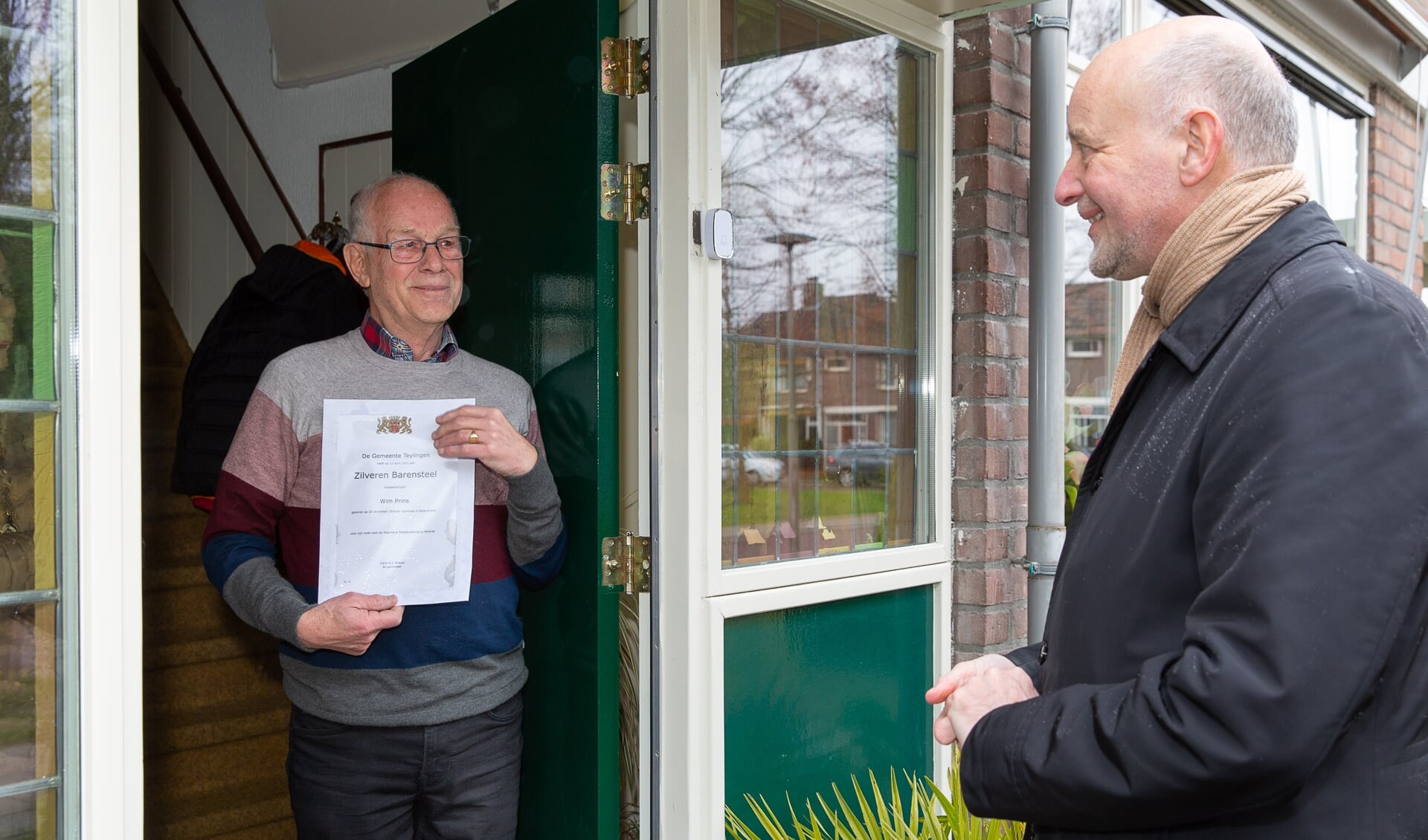 Wim Prins ontvangt aan de deur de Zilveren Barensteel van wethouder Arno van Kempen. 