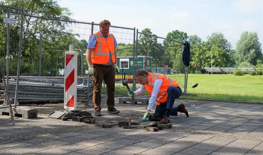 <p>Wethouder Rik van Woudenberg heeft de steen op z&#39;n plek gelegd, zijn collega Willem Joosten hamert &#39;m vast.&nbsp;</p>  