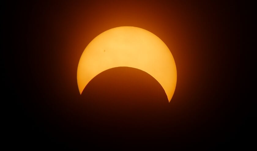 De maan dekt een deel van de zon af.