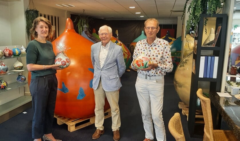<p>Joost Paijmans, president van de Lions Lisse Oude Duinen, overhandigt de mini-bol aan de winnares Ivalda Booij. Rechts op de foto Jan van Vliet, trekker van het Reuzenbollen-project.</p>