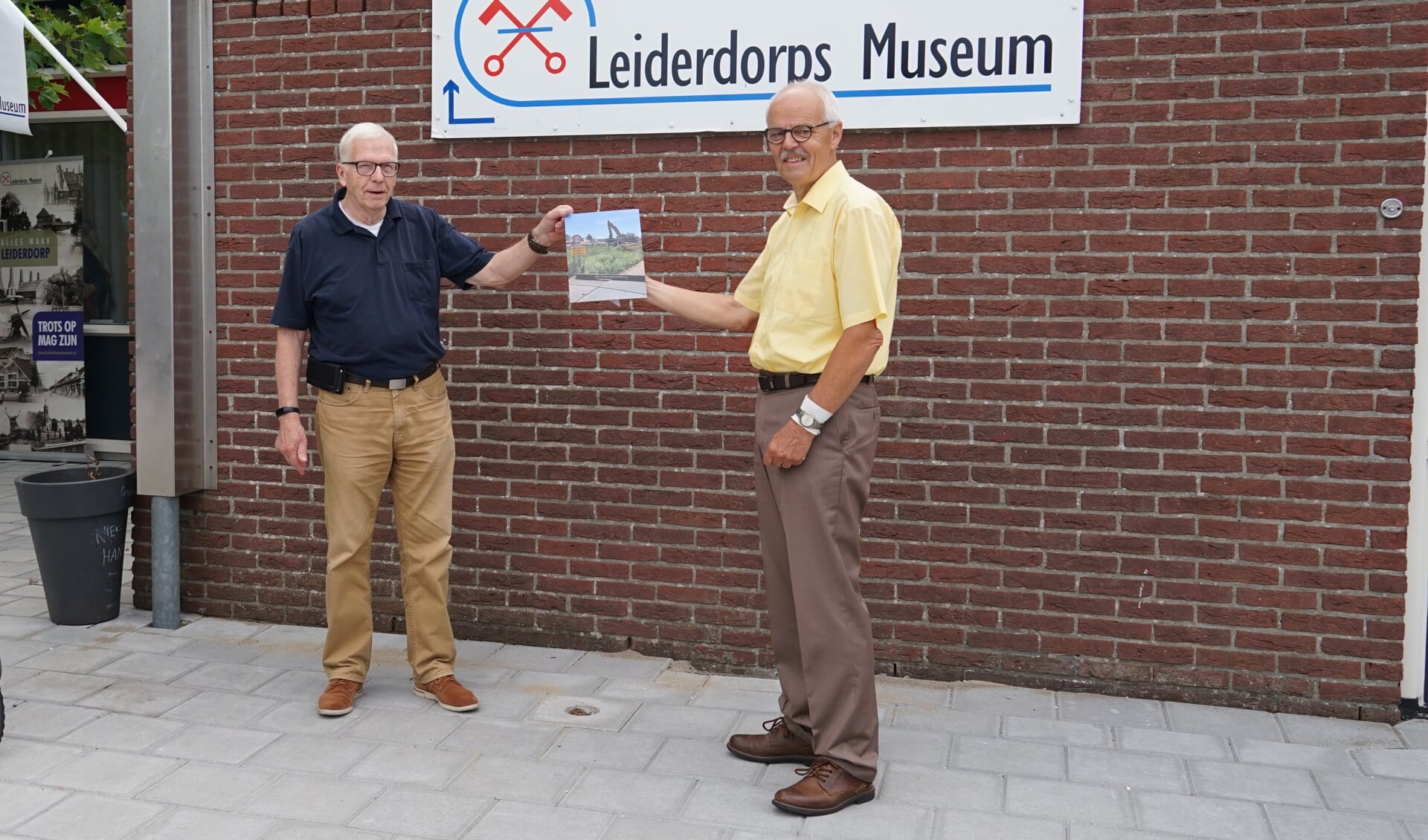 Joop van Huut (rechts) overhandigt een foto van het naambord aan Bob Reidsma van het Leiderdorps Museum. 