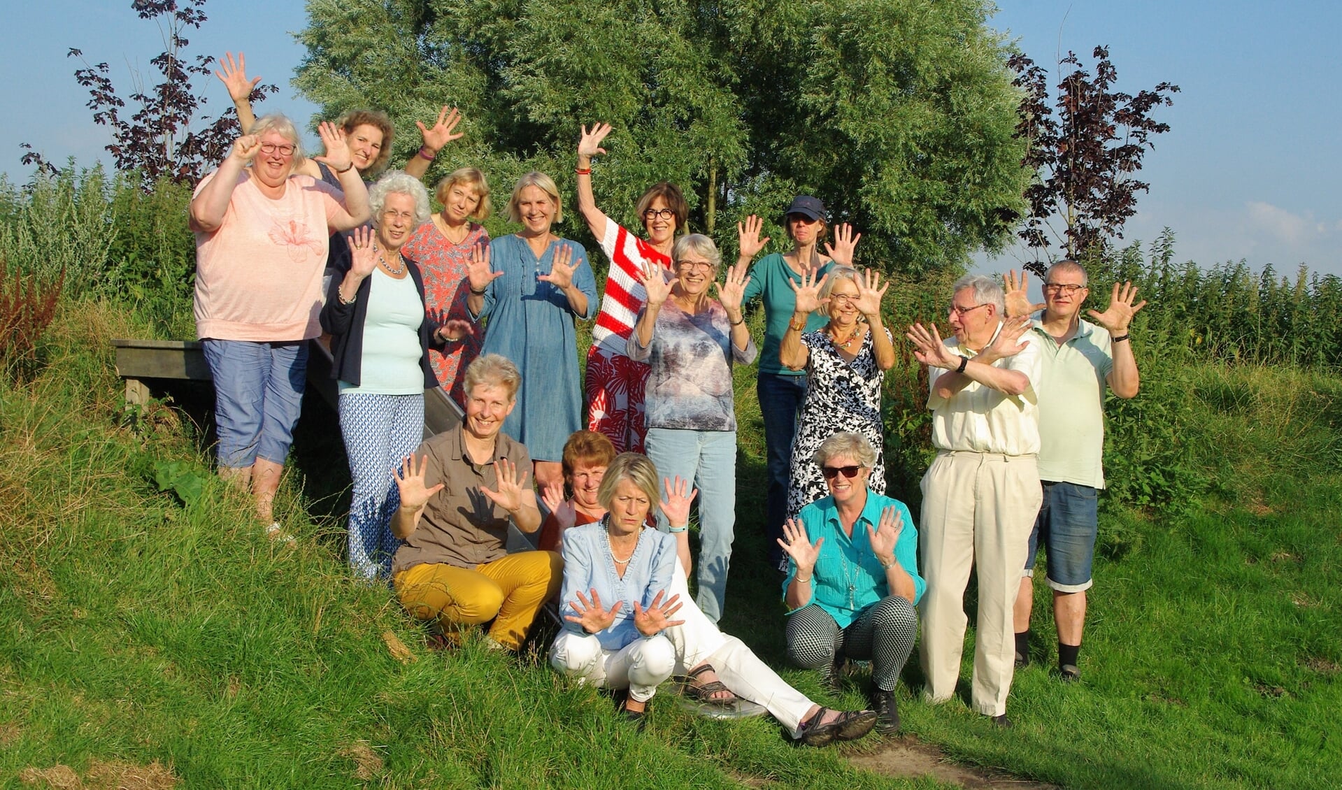 Vijftien enthousiaste Wandelclub-deelnemers poseren voor een jubileumfoto in de zon. |