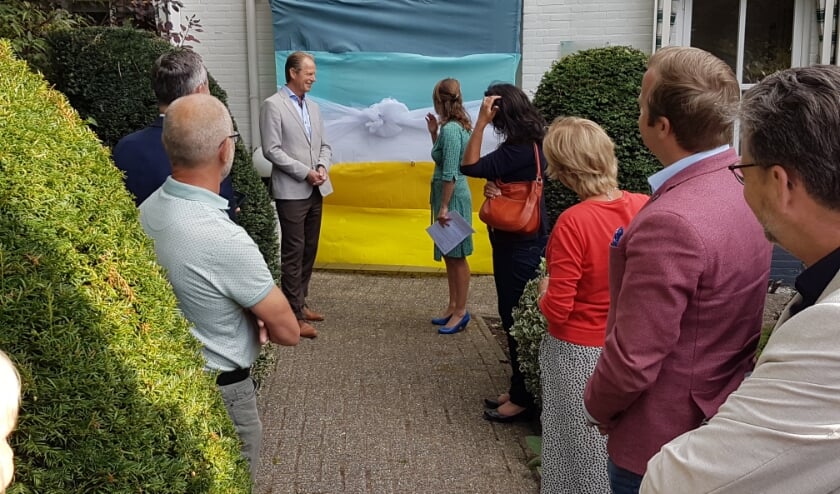 <p>Genodigden konden meekijken hoe Arie Van Erk de strik losmaakte van de ingepakte voordeur. | Foto: PR.</p>