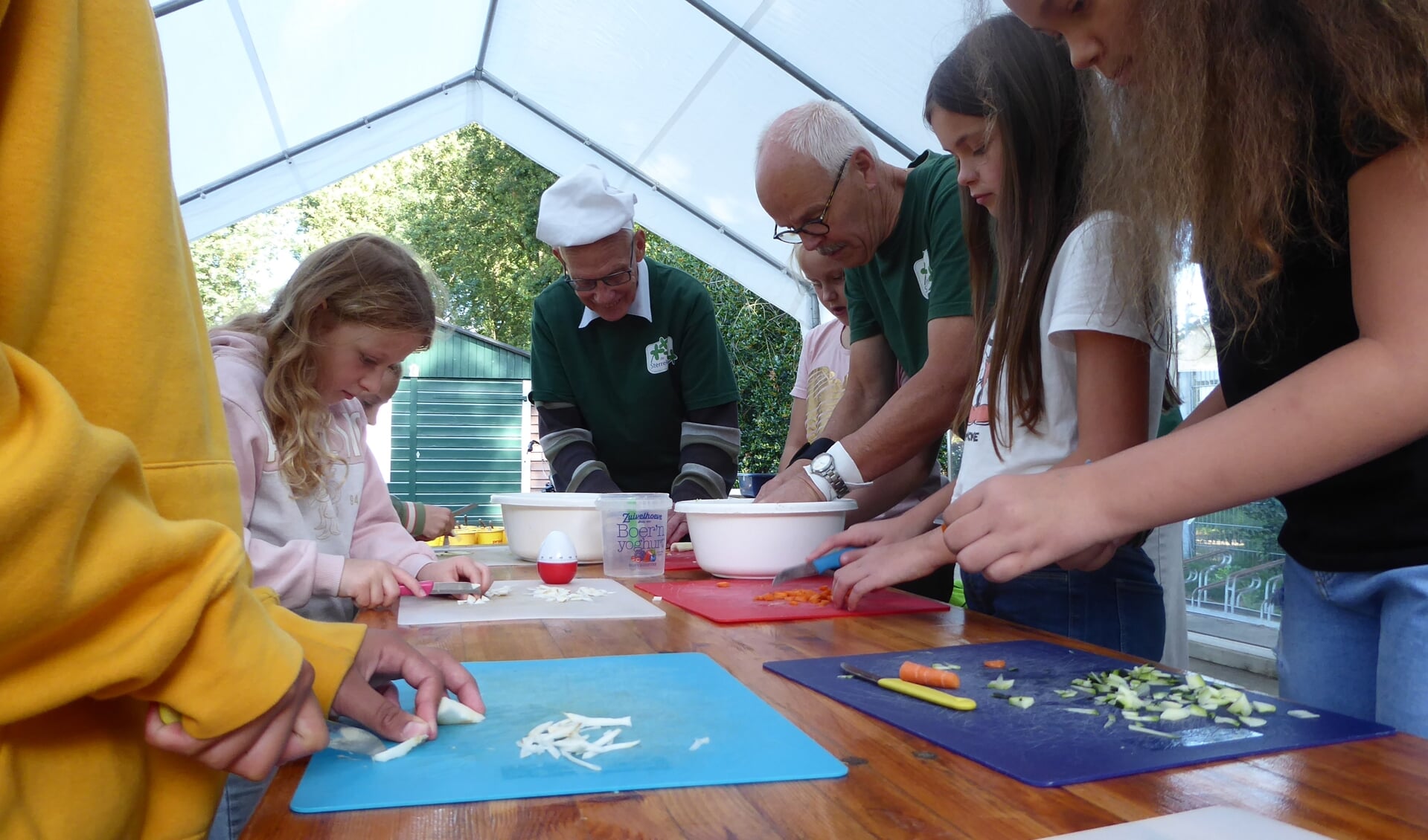 Leerlingen van de Regenboogschool snijden de groente met hulp van vrijwilligers. 