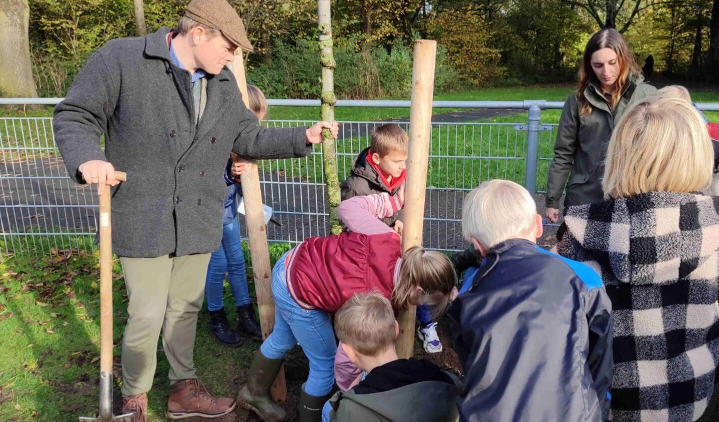 Samen met leerlingen van groep 6 van de Schakel zet wethouder Bob Vastenhoud (met pet) Harry de fladderiep stevig in de grond.