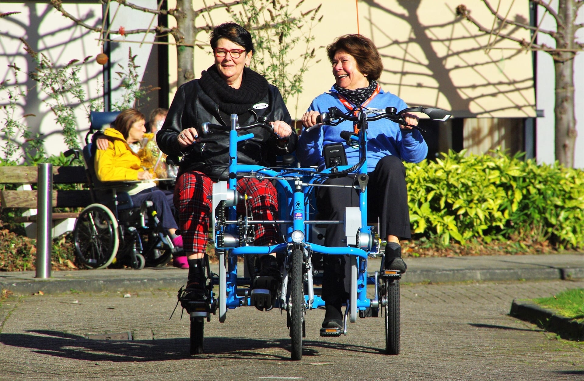 Locatiemanager Marjolein Post en fietsmaatje Marijke in 't Veld rijden de nieuwe duofiets naar zijn nieuwe plek. |