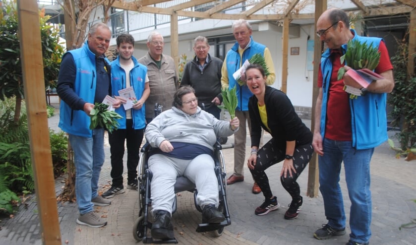 Commissieleden Rob van der Groen, Fred van Setten (1e en 3e van rechts) en Koos Koster (geheel links) delen tulpen uit in het atrium van het seniorencomplex aan de Bloemendaalselaan. 2e van rechts Nathalie Beekman, de fitnesstrainer die het Balkon Bewegen leidt.