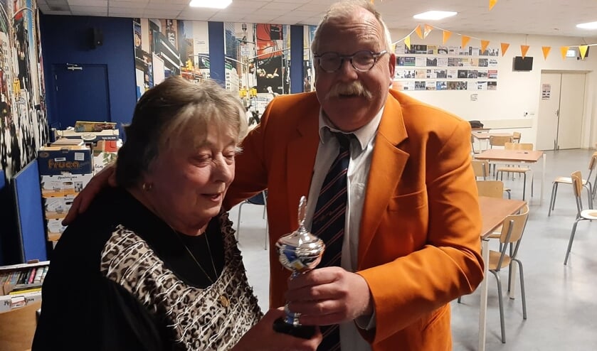 
Sonja Blok krijgt de wisselbeker van de Oranjeklaverjasavond van bestuurslid Arno Mentinkvan de Oranjevereniging.  