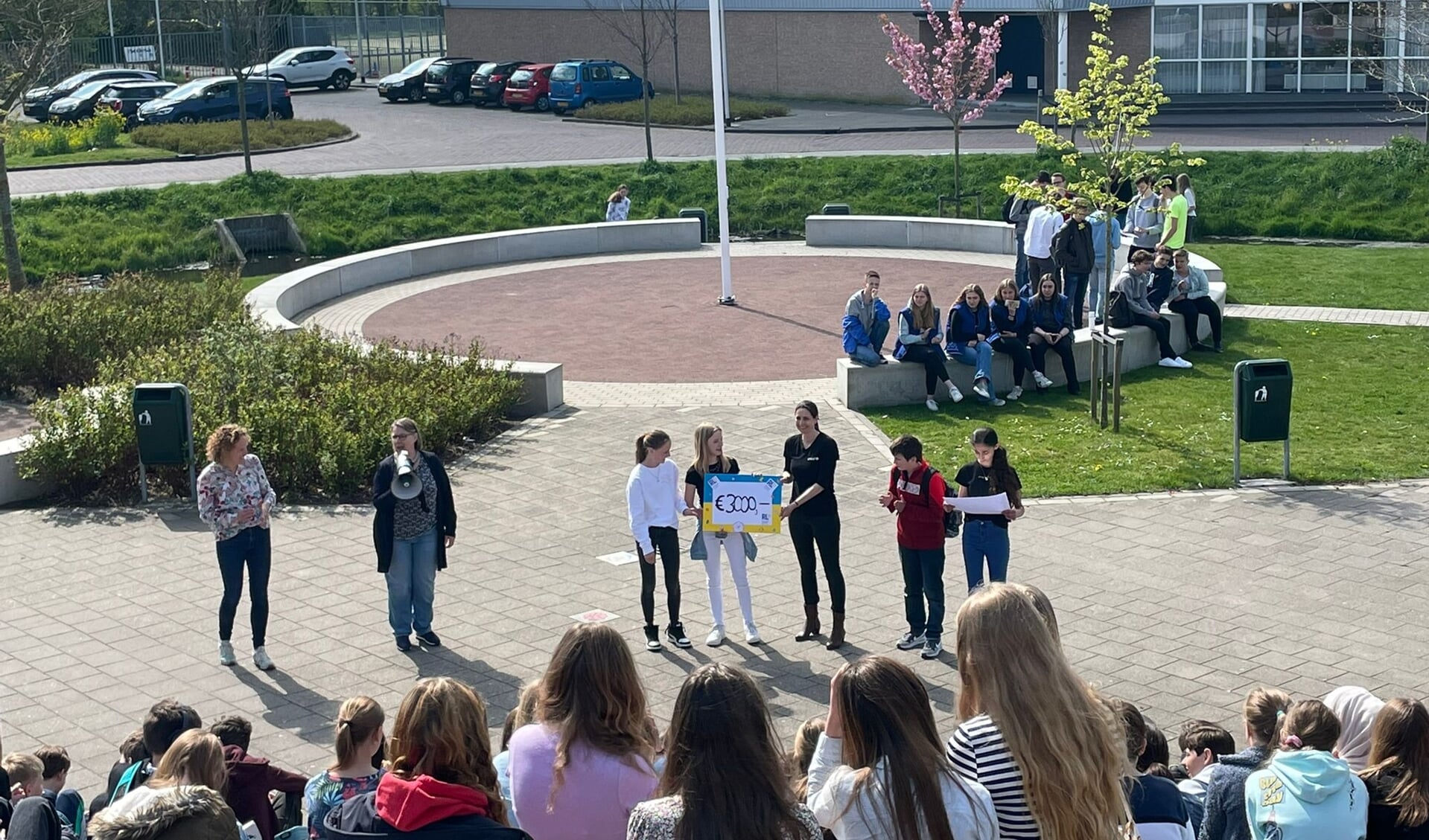 Leerlingen overhandigen symbolisch 3.000 euro opbrengst van hun voorjaarsmarkt, aan Unicef-vertegenwoordiger Esther Vreeburg, voor hulp aan Oekraïne.
