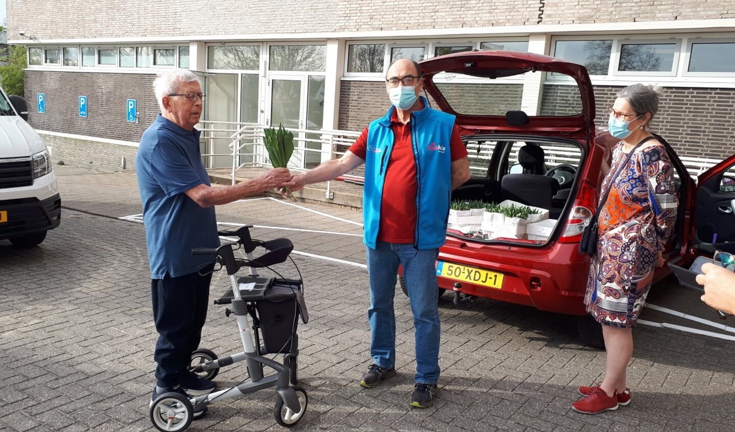 Rob van der Groen van Clubhuis De Derde Helft (midden) levert tulpen af bij verpleeghuis Leythenrode.