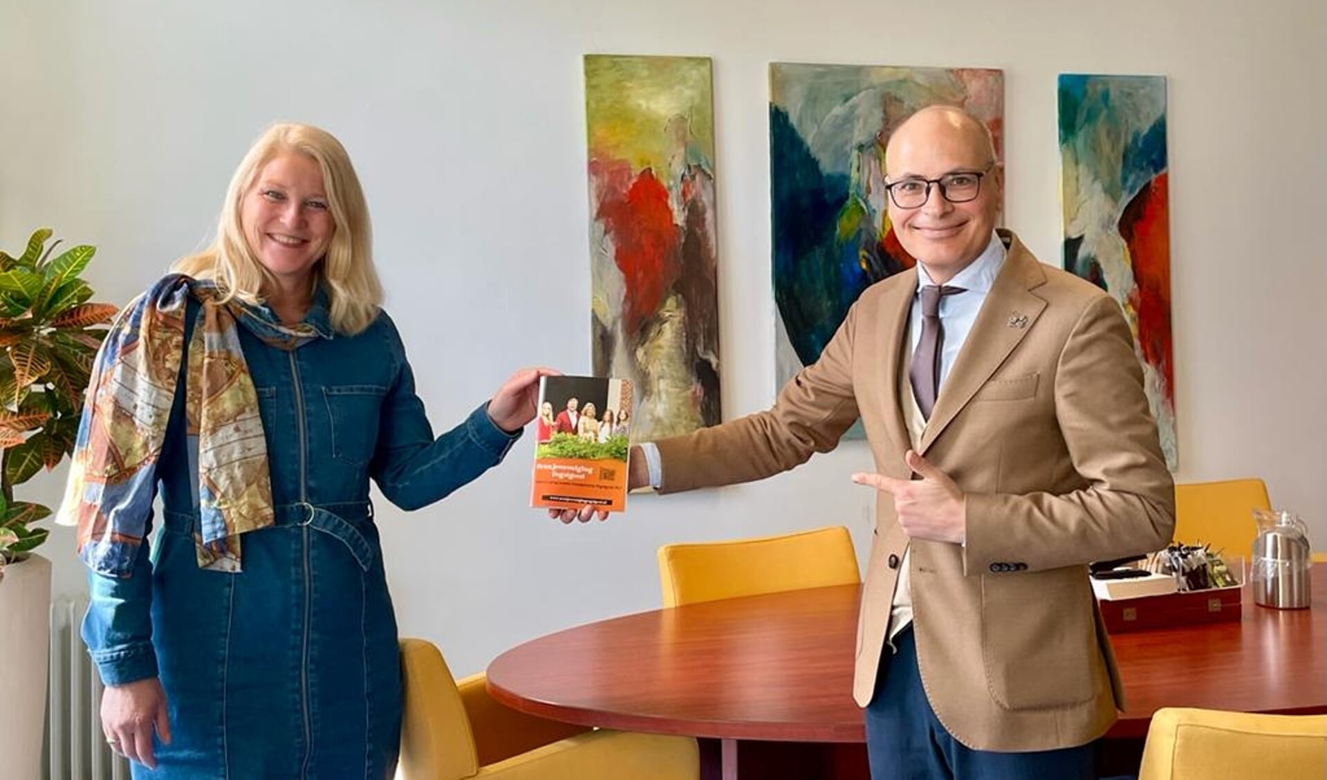 Burgemeester Emile Jaensch neemt het eerste programmaboekje in ontvangst van Oranjeverenigingvoorzitter Linda van der Zon.
