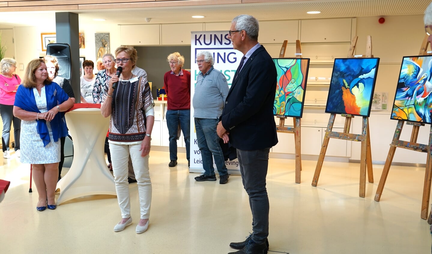 Voorzitter Ellen Cazemier van de Kunstkring Leiderdorp heet de aanwezigen welkom. Rechts staat cultuurwethouder Herman Romeijn die de tentoonstelling opende.   