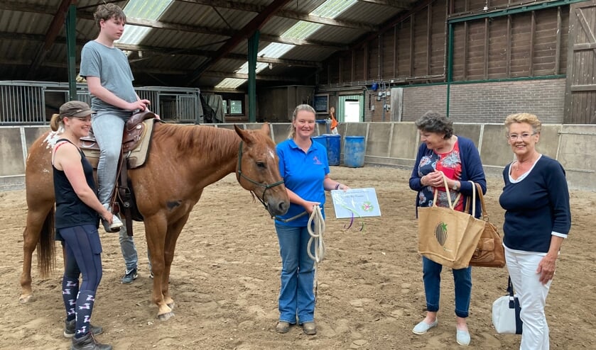 <p>Bestuurslid Sigrid Kunnen met de cheque van de dames van de Kringloop Voorhout. Op het paard zit Nathan. </p>