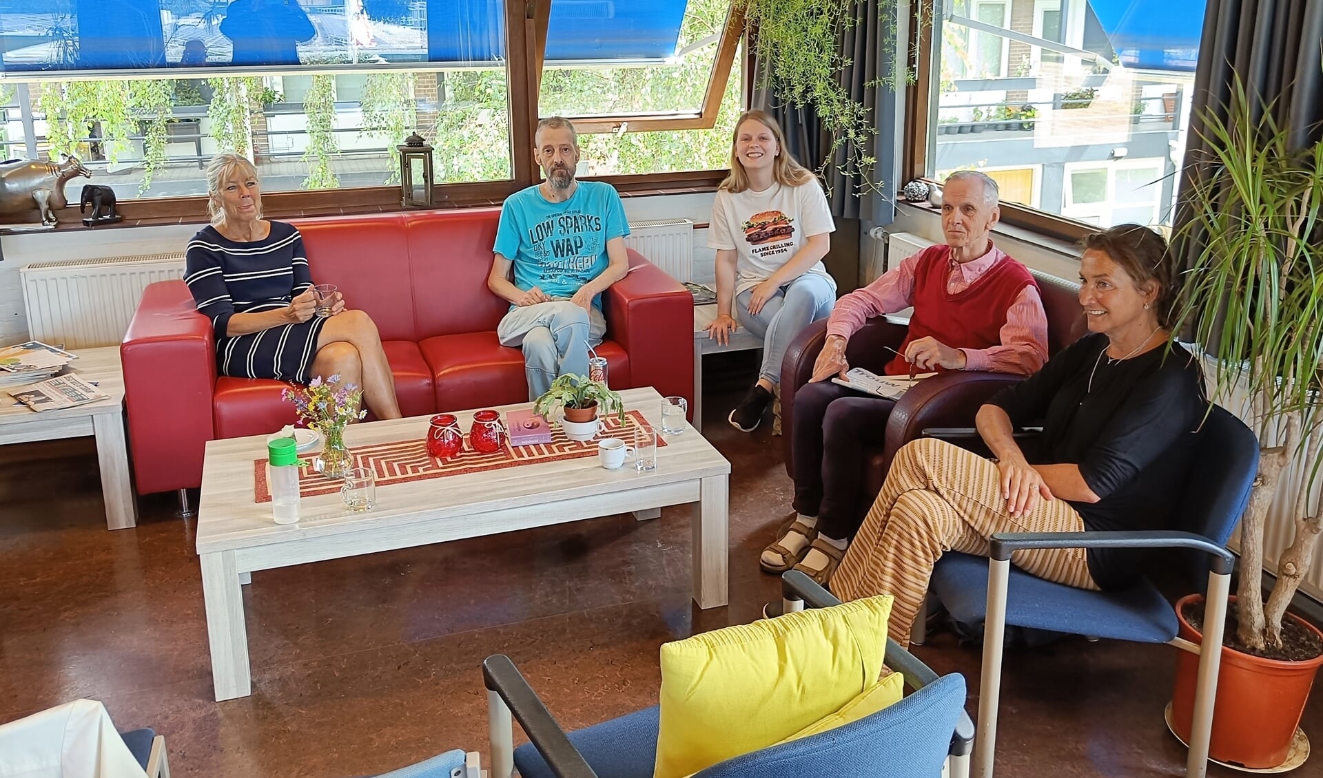 Lynn (midden) in gesprek met bezoekers en medewerkers van het inloophuis van Lumen in Dorpscentrum Oegstgeest. 