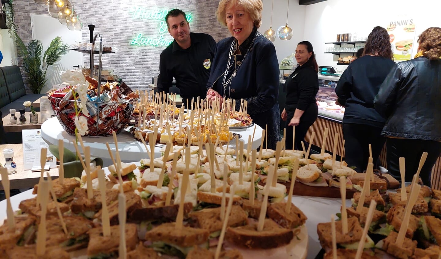 Burgemeester Driessen bekijkt het lunchbuffet in Multivlaai. Achter haar staat eigenaar Ashour Dengha.
