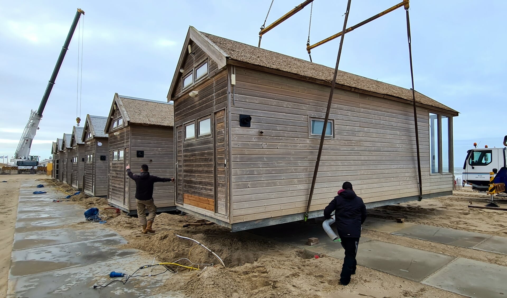 Een grote kraan zet een strandhuisje weer op zijn plek. | Foto: Johan Westra