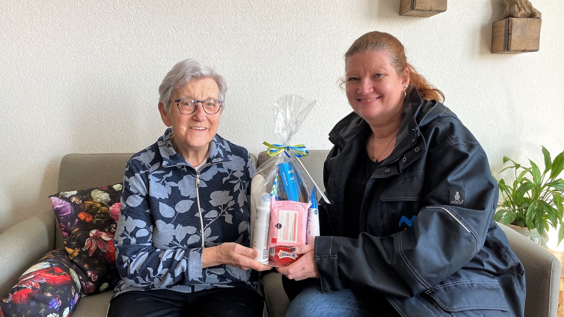 Wijkbeheerder Tanja van der Wal biedt mevrouw van Klink een pakketje aan namens een dankbare buur.